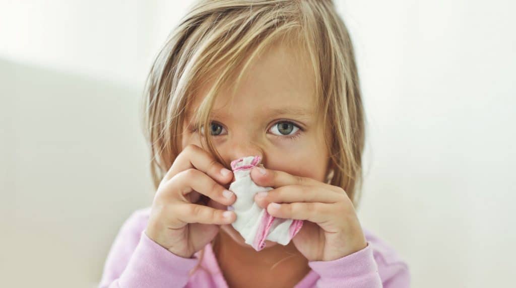 Little girl suffering from a blocked nose and nasal congestion as a result of the common cold, desperately in need of nasal spray
